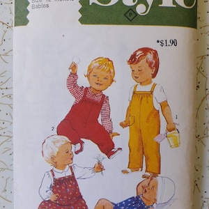 May include: Vintage sewing pattern for babies, size 12 months. The cover features illustrations of four babies in different outfits, including overalls and a romper. The word "Style" is prominently displayed at the top.