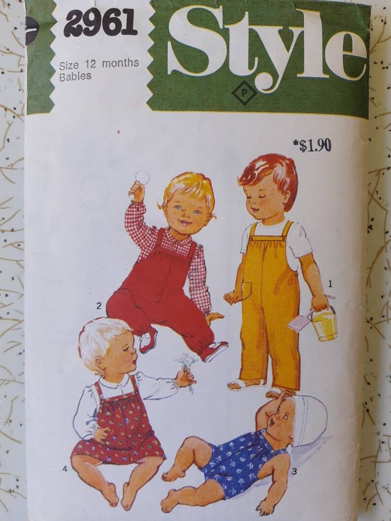 May include: Vintage sewing pattern for babies, size 12 months. The cover features illustrations of four babies in different outfits, including overalls and a romper. The word "Style" is prominently displayed at the top.