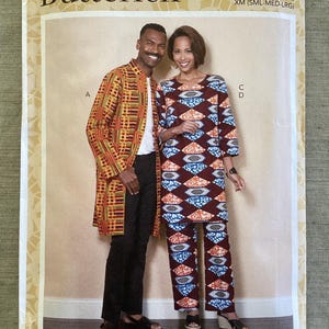 May include: A Butterick sewing pattern package featuring a man and woman modeling clothing. The man wears a long, patterned coat over black pants. The woman models a matching top and pants set with a geometric design. The package is labeled B6534.