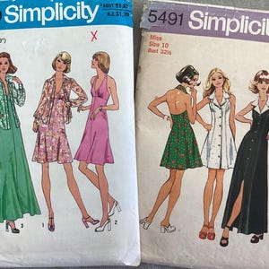 Può includere: Due buste di cartamodelli Simplicity vintage. Una presenta illustrazioni di tre abiti, tra cui un abito lungo verde e un abito rosa all'americana. L'altra mostra un abito floreale verde, un abito bianco abbottonato e un abito nero con spacco.