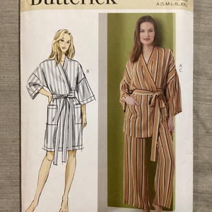 Könnte beinhalten: Ein Butterick-Schnittmusterumschlag mit Illustrationen von zwei gestreiften Roben. Der Umschlag enthält die Schnittmusternummer B7047 und die Größenoptionen A (S-M-L-XL-XXL). Die Roben sind in einem hellgrauen und braunen Farbschema dargestellt.