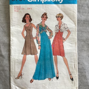 May include: Simplicity sewing pattern 6761 for size 12, featuring a bust measurement of 87 cm. The envelope displays illustrations of three different dress styles: a sleeveless tan dress, a long blue dress with a floral bolero, and a red polka-dot dress with a white collar.