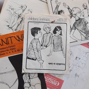 May include: A collection of vintage sewing patterns for knit tops, pants, and shorts. The patterns are printed on white paper with black ink and feature illustrations of children wearing the garments. The patterns are labeled with sizes and instructions for sewing.