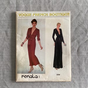 Könnte beinhalten: Vintage Vogue French Boutique Schnittmuster mit zwei Kleiderdesigns. Das Cover zeigt einen roten Jumpsuit und ein schwarzes Kleid, beide mit tiefem Ausschnitt. Das Schnittmuster ist mit "renata paris" gekennzeichnet und enthält die Nummer 2254.
