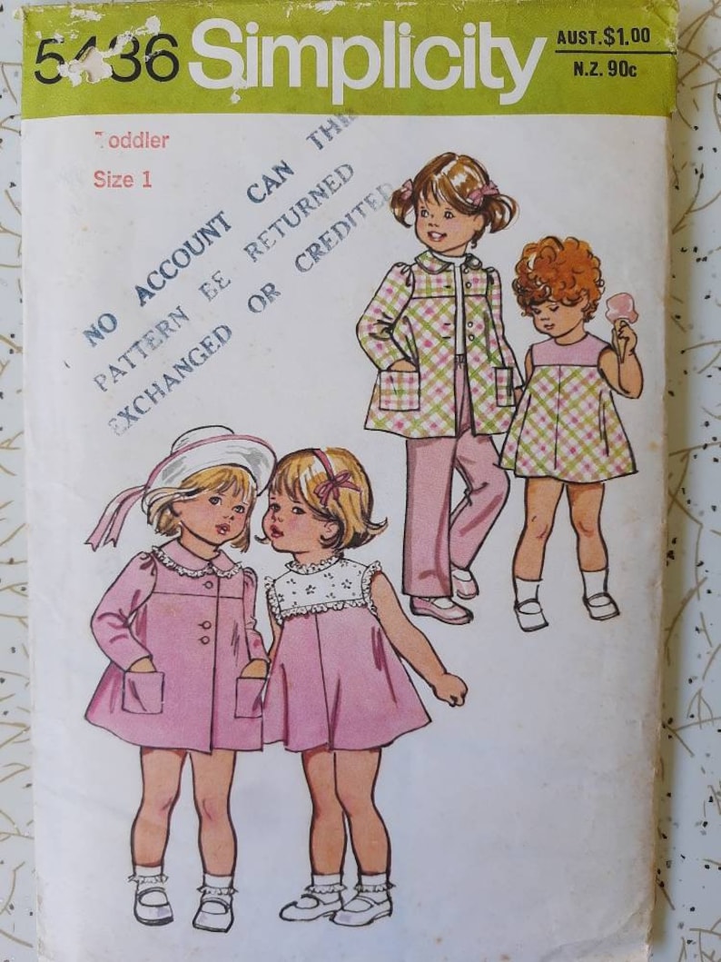 May include: A vintage Simplicity sewing pattern for toddler clothing, featuring illustrations of children's outfits. The pattern includes a pink coat, dress, and plaid jacket and pants set. The pattern number is 5436.