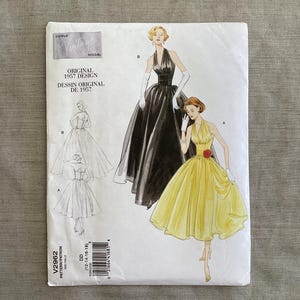 Puede incluir: Un patrón de costura Vogue vintage con ilustraciones de dos vestidos con cuello halter, uno negro y otro amarillo. El patrón está etiquetado como "Original 1957 Design" e incluye el número de patrón V2962. La portada tiene una estética vintage.
