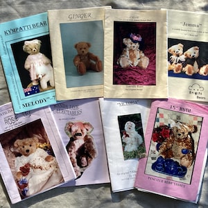 Peut inclure: Une collection de patrons de nounours vintage. Les couvertures présentent des images d'ours en peluche dans divers styles et environnements. Les titres incluent "Ginger", "Jemma" et "15" Ruth". Les livres sont disposés sur une surface claire.