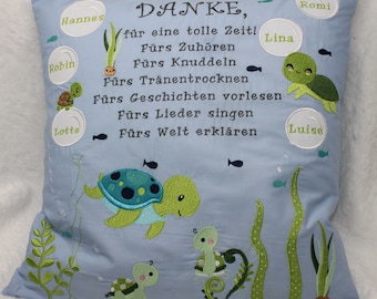 May include: A light blue pillow with embroidered text that says "DANKE, für eine tolle Zeit! Fürs Zuhören Fürs Knuddeln Fürs Tränentrocknen Fürs Geschichten vorlesen Fürs Lieder singen Fürs Welt erklären". The pillow also has embroidered images of sea turtles and seaweed.