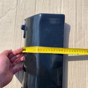 K&ouml;nnte beinhalten: Ein dunkelblaues, rechteckiges Objekt mit einem Ma&szlig;band, das eine L&auml;nge von etwa 25 cm anzeigt. Das Objekt hat zwei kleine, hervorstehende Merkmale an der Seite. Das Ma&szlig;band ist gelb mit schwarzen Markierungen.