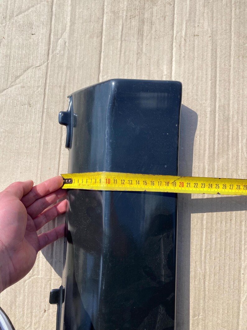 K&ouml;nnte beinhalten: Ein dunkelblaues, rechteckiges Objekt mit einem Ma&szlig;band, das eine L&auml;nge von etwa 25 cm anzeigt. Das Objekt hat zwei kleine, hervorstehende Merkmale an der Seite. Das Ma&szlig;band ist gelb mit schwarzen Markierungen.