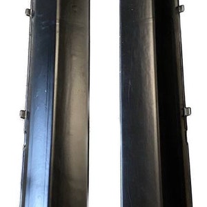 K&ouml;nnte beinhalten: Zwei schwarze Seitenschweller aus Kunststoff, wahrscheinlich f&uuml;r ein Fahrzeug, werden vor wei&szlig;em Hintergrund gezeigt. Jedes Teil ist lang und abgewinkelt, mit mehreren Befestigungspunkten und gl&auml;nzendem Finish. Autoteile.