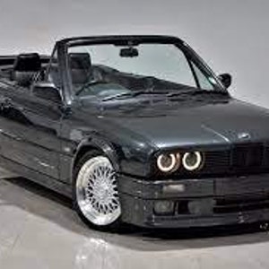 K&ouml;nnte beinhalten: Ein dunkelgraues Cabrio mit schwarzem Innenraum. Das Auto hat ein schlankes Design mit silbernen Felgen und hellen Scheinwerfern. Das Verdeck ist ge&ouml;ffnet und gibt die Sitze und das Armaturenbrett frei. Das Auto scheint in ausgezeichnetem Zustand zu sein.