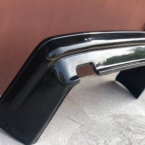 May include: A black plastic car bumper replacement part. The bumper is designed to fit a specific car model.