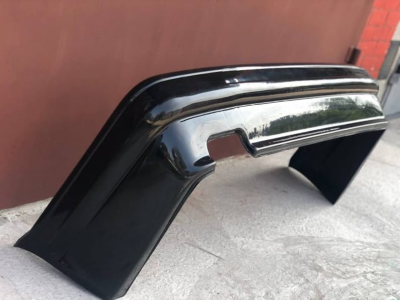 May include: A black plastic car bumper replacement part. The bumper is designed to fit a specific car model.
