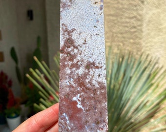May include: A white, blue, and brown agate obelisk crystal point. The crystal is polished and has a smooth, glassy surface.