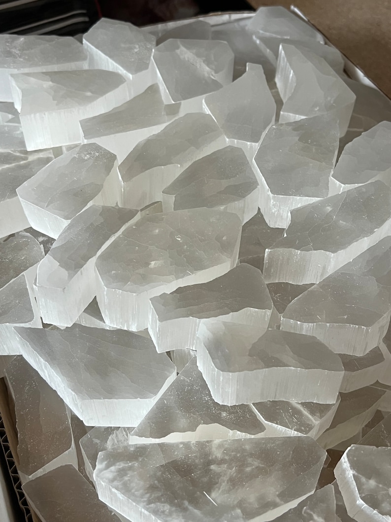 May include: A pile of selenite crystal pieces in various sizes and shapes. The crystals are translucent white and have a smooth, polished surface.