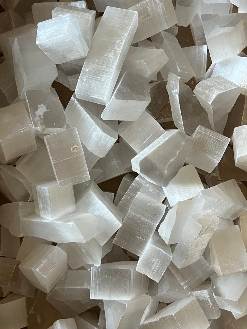 May include: A pile of white selenite crystal pieces. The crystals are rough and have a natural, unpolished look. They are all different sizes and shapes.