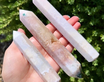 May include: Three white, pink, and green crystal wands with pointed ends. The wands are smooth and polished.