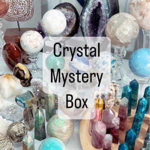 Pode incluir: Uma coleção de cristais e pedras preciosas, incluindo esferas, geodos e pontas polidas. A imagem apresenta uma variedade de cores e texturas, com o texto "Crystal Mystery Box" sobreposto.