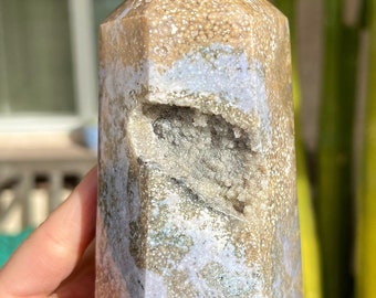 Op de afbeelding: Een bruine en witte kristallen punt met een natuurlijke, druzy afwerking. De kristal heeft een uniek, draaiend patroon en een heldere, glazige uitstraling.