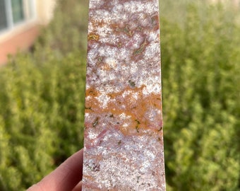 Op de afbeelding: Een bruine, witte en rode agaat kristallen punt met een puntige punt. Het kristal heeft een natuurlijke, ruwe textuur en is een prachtig voorbeeld van dit type steen.