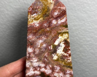 May include: A red, white, and green jasper point with a unique swirling pattern. The point is polished and has a smooth, glossy finish.