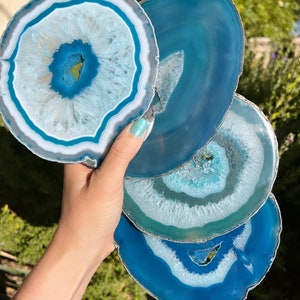 May include: A selection of blue and white agate coasters. Each coaster features a unique pattern of concentric rings, with shades of blue, white, and grey. The coasters are round and vary slightly in size, showcasing natural stone variations.