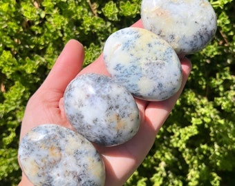 May include: Four smooth, oval-shaped stones with a white, gray, and yellow mottled pattern. The stones are arranged in a row, with the largest stone at the top and the smallest stone at the bottom.