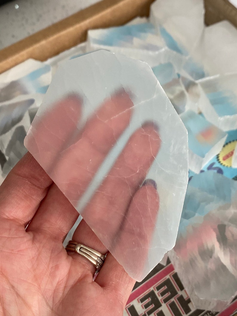 May include: A translucent white selenite crystal slab with a slightly irregular shape. The crystal is smooth and has a subtle sheen.