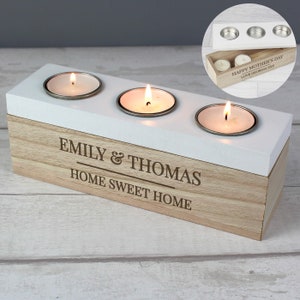 May include: A wooden candle holder with three candle slots. The holder is engraved with the names "Emily & Thomas" and the phrase "Home Sweet Home".