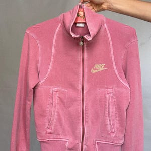 K&ouml;nnte beinhalten: Eine wei&szlig;e Keramik-Tasse mit schwarzem Henkel und dem Text "But First, Coffee" in schwarzer, handschriftlicher Schrift. Die Tasse steht auf einer wei&szlig;en Oberfl&auml;che.