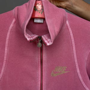 K&ouml;nnte beinhalten: Eine wei&szlig;e Keramik-Tasse mit schwarzem Henkel und dem Text "But First, Coffee" in fetter, schwarzer Schrift. Die Tasse steht vor einem verschwommenen Hintergrund, der eine gem&uuml;tliche Umgebung suggeriert.