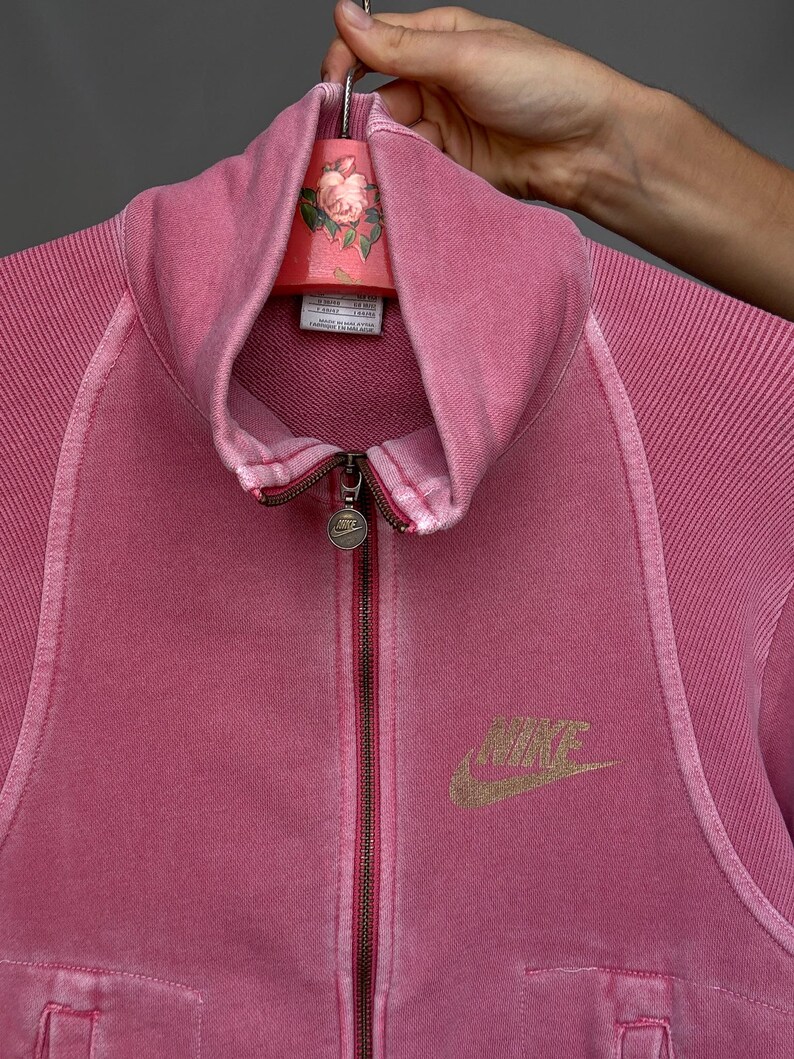 K&ouml;nnte beinhalten: Eine wei&szlig;e Keramik-Tasse mit schwarzem Henkel und dem Text "But First, Coffee" in fetter, schwarzer Schrift. Die Tasse steht vor einem verschwommenen Hintergrund, der eine gem&uuml;tliche Umgebung suggeriert.