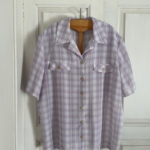 May include: A lavender and white plaid button-up shirt with short sleeves and two chest pockets.