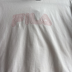 May include: White hooded sweatshirt with the brand name "FILA" in pink lettering. The sweatshirt has a black hood and a black band at the bottom. The fabric appears to be a soft, textured material.