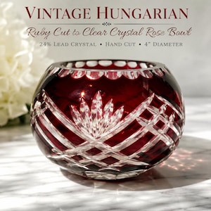 May include: A vintage Hungarian ruby cut-to-clear crystal rose bowl featuring intricate hand-cut geometric and floral patterns. The bowl is made of 24% lead crystal and measures 4 inches in diameter. The text reads VINTAGE HUNGARIAN Ruby Cut to Clear Crystal Rose Bowl 24% Lead Crystal Hand Cut 4" Diameter.
