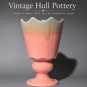 Puede incluir: Un jarrón de pedestal de cerámica Hull Pottery vintage con una base rosa y un esmalte gris que gotea en el borde festoneado. El texto "Vintage Hull Pottery" y "PINK & GRAY DRIP GLAZE PEDESTAL VASE" aparece sobre el recipiente.