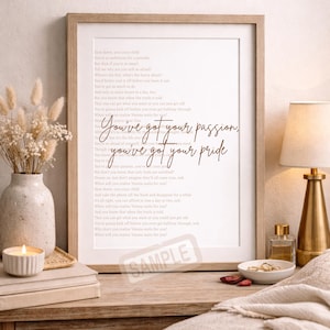 May include: A framed print with a poem in a light brown font. The text "You've got your passion, you've got your pride" is in a cursive font. The frame is light brown and the print is displayed on a wooden surface.