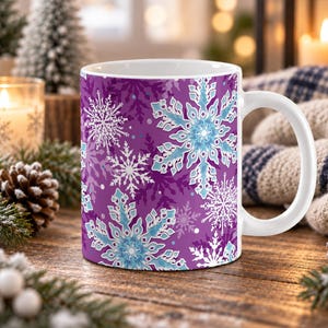 May include: A white ceramic mug featuring a vibrant purple background decorated with a repeating pattern of intricate snowflakes in shades of light blue, white, and darker purple. The mug has a smooth handle and a clean, white interior rim.