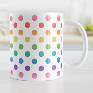 May include: White ceramic mug with a rainbow polka dot pattern. The dots are arranged in rows and are different shades of red, orange, yellow, green, blue, purple, and pink.