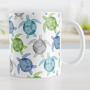May include: White ceramic mug with a repeating pattern of blue, green, and gray sea turtles with floral designs.