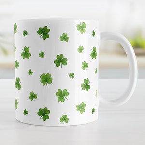 May include: White ceramic mug with a repeating pattern of green four-leaf clovers.