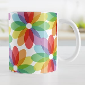 May include: White ceramic mug with a colorful abstract floral design. The design features overlapping circles in shades of red, orange, yellow, green, blue, and purple.