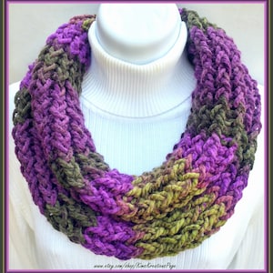 May include: A purple and green infinity scarf made of chunky yarn. The scarf is knit in a cable stitch pattern.