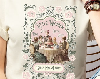 Könnte beinhalten: Ein weißes T-Shirt mit einer Vintage-Illustration des Covers des Buches "Little Women" von Louisa May Alcott. Die Illustration zeigt vier Mädchen, die um einen Tisch mit einer Teekanne und Teetassen sitzen. Der Text "Little Women" ist in einem rosa Banner mit den Namen der Figuren Meg, Jo, Beth und Amy darunter aufgeführt. Das T-Shirt wird von einem Model getragen, das blaue Jeans trägt.