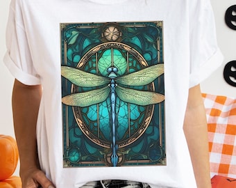 May include: White t-shirt with a graphic of a blue and green dragonfly in a stained glass style frame.