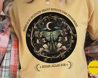 May include: A mustard yellow t-shirt with a black circle graphic featuring a moth, crescent moon, and floral design. The text "THERE IS NO EXQUISITE BEAUTY WITHOUT SOME STRANGENESS" is written around the circle. The text "EDGAR ALLAN POE" is written below the circle.