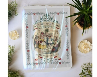 Peut inclure: Une couverture de livre vintage avec une illustration festive d'une scène de fête de Noël. La couverture porte le titre "A Christmas Carol" et le texte "Mr. Fezziwig's Ball".