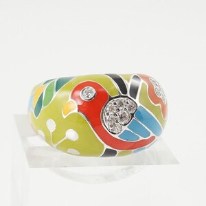 May include: A green, red, blue and white enamel ring with a bird design and clear gemstones.