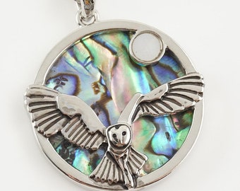 May include: A silver necklace with a round pendant featuring an iridescent abalone shell with a silver owl flying in front of it. The owl has a white moonstone in its eye.